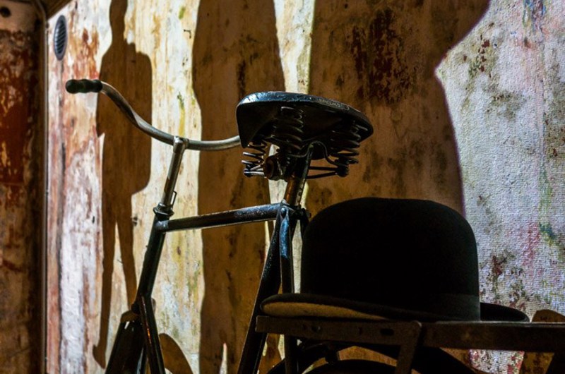 Udstillingsrum med gammeldags cykel og projektion på væg