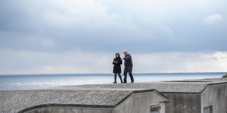 To personer går på toppen af Mosede Fort med udsigt over Køge Bugt