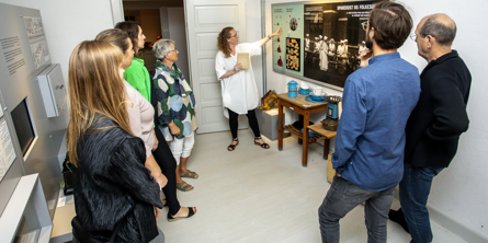 Gruppe ser museumsinspektør Louise Ahmt vise en plakat i udstillingen