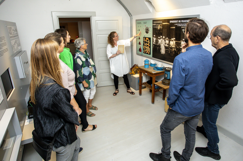 Gruppe ser museumsinspektør Louise Ahmt vise en plakat i udstillingen